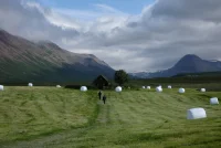 A photo of the oldest church in Iceland with hayballs on the field